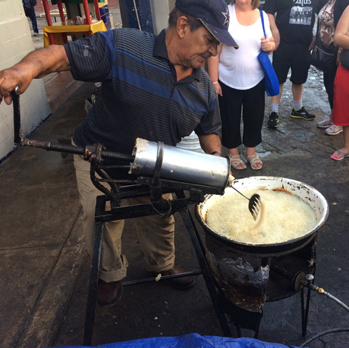 Street vendor frying dough to make churros (Mexican donuts) in small town Pitillal, Mexico. 