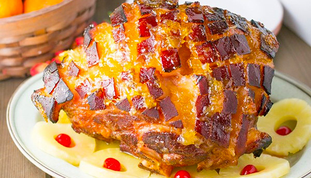Pineapple-glazed ham is covered in pineapple jam and then baked in the oven until skin is crisp and brown.