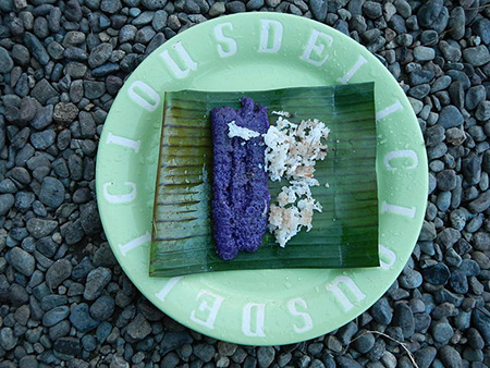 Puto bumbong, a purple-coloured sticky rice cake shaped like small logs and flavoured with brown sugar, margarine or butter, and fresh grated coconut, is sold outside churches in December. Photo by Ramon FVelasquez.